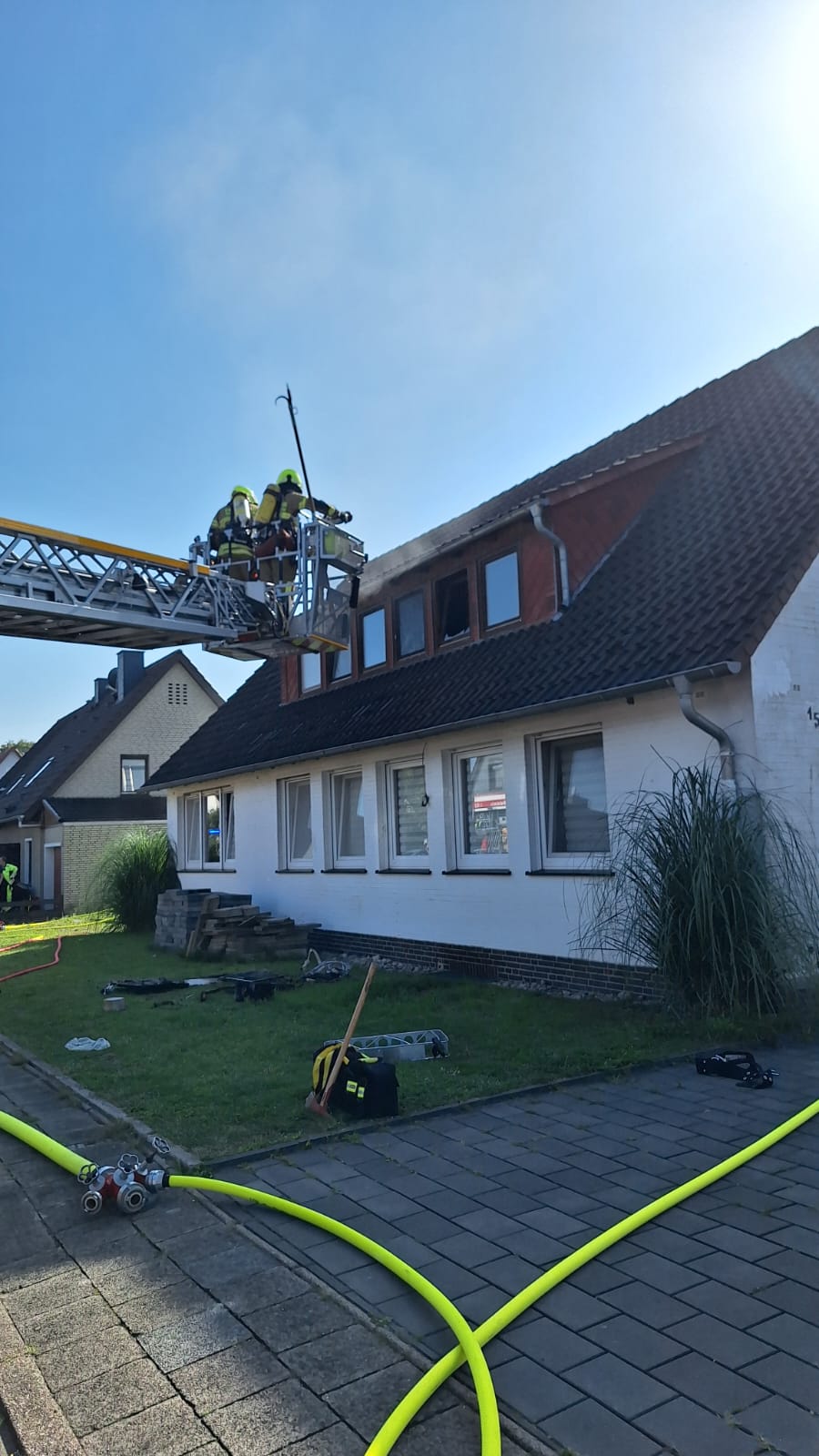 Feuerwehrleute auf Drehleiter vor Haus in Einsatz.
