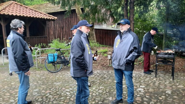 Männer grillen vor Holzhütte im Grünen