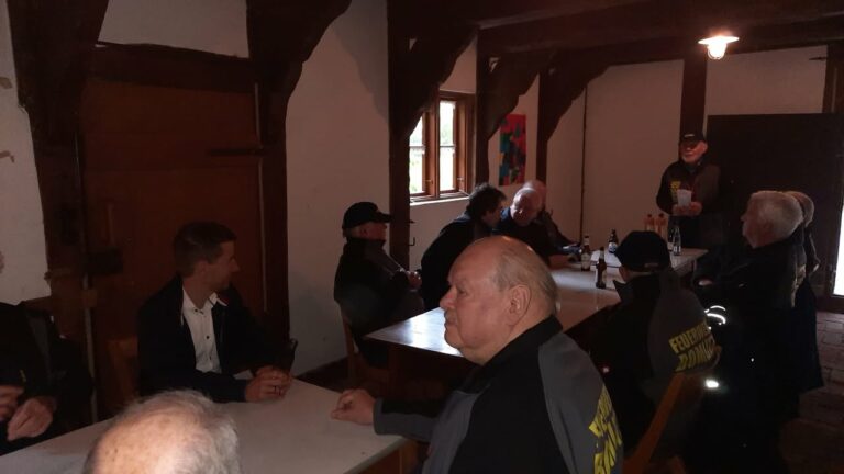 Männer sitzen in rustikalem Raum an Tischen