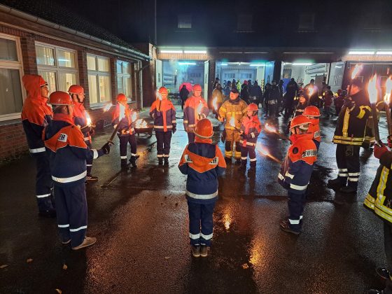 Jugendfeuerwehr mit Fackeln auf nassglänzendem Boden