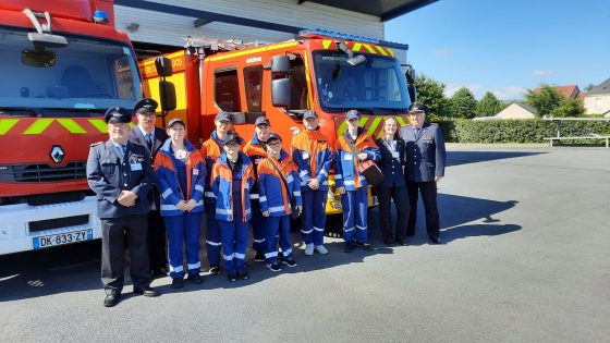 Gruppe von Einsatzkräften vor Feuerwehrfahrzeug.