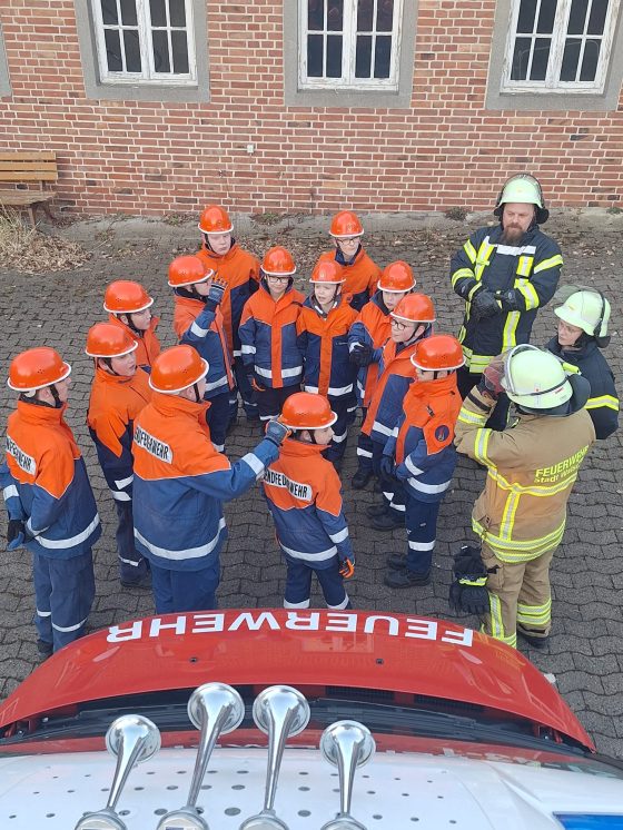 Jugendfeuerwehr in orangen Helmen und Uniformen