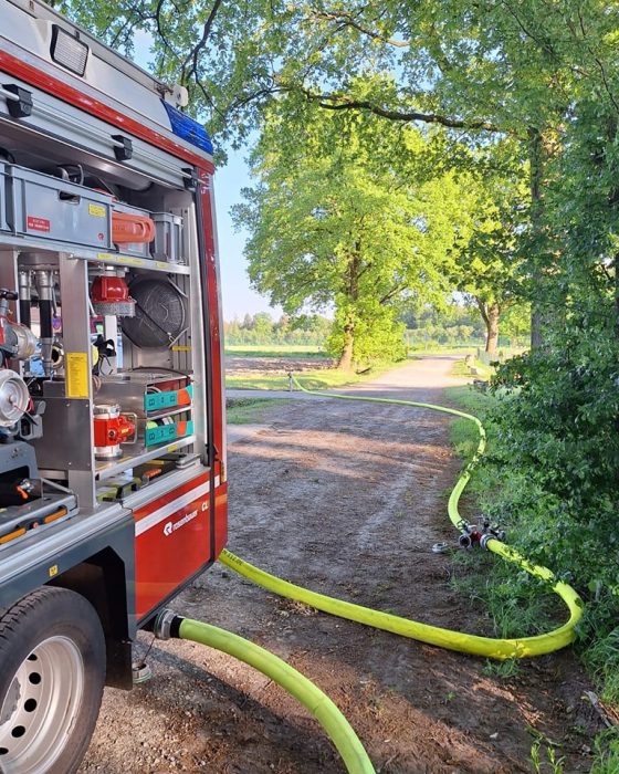 Feuerwehrfahrzeug mit Schlauch im Waldweg