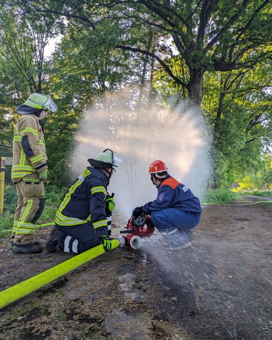 Feuerwehrleute trainieren mit Wasserschlauch im Freien.