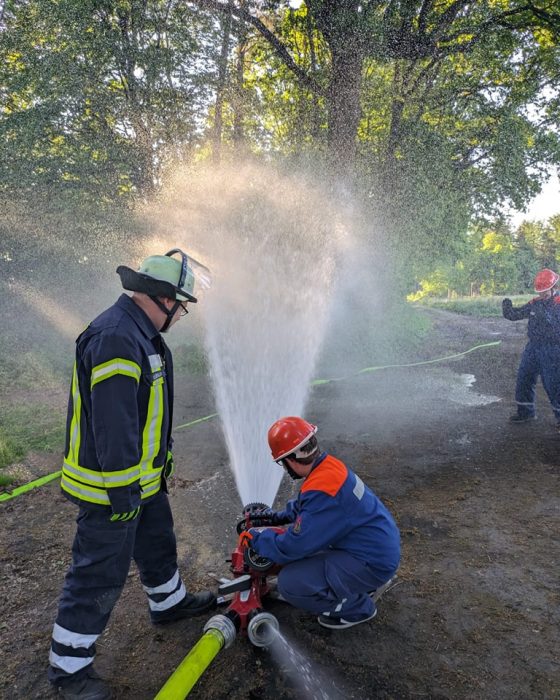 Feuerwehrleute bedienen einen Wasserhydranten im Freien.
